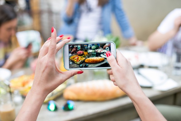 Woman taking a photo of breakfast with smartphone
